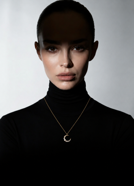 Femme portant un collier croissant de lune doré serti de zircons LUNARA, col roulé noir, style éditorial premium fond gris