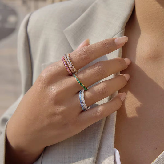 Bague Julia LUNARA – bague éternité empilable pavée de pierres colorées blanc bleu vert rose, tenue à la main
