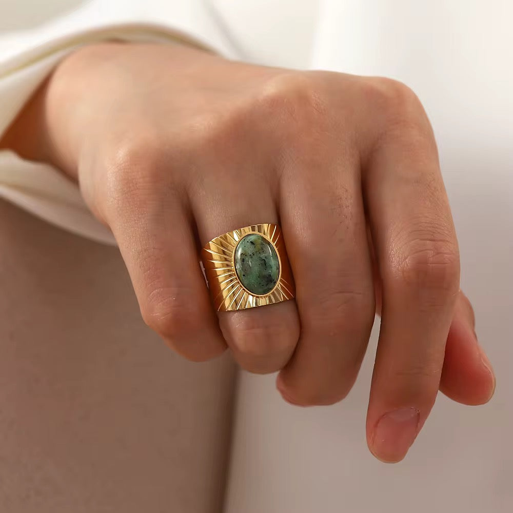 Bague Sandro LUNARA – chevalière solaire turquoise portée à la main, vue de face sur fond beige